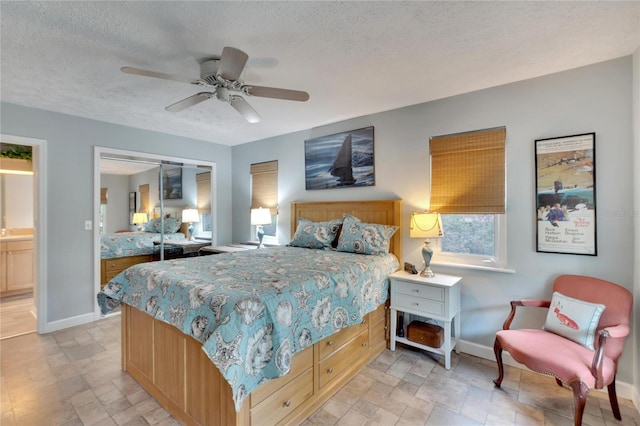 bedroom with ceiling fan, ensuite bathroom, a textured ceiling, and a closet