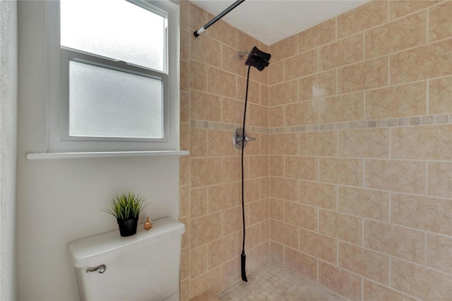 bathroom featuring tiled shower and toilet