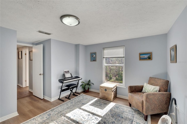 living area with light wood-type flooring and a textured ceiling