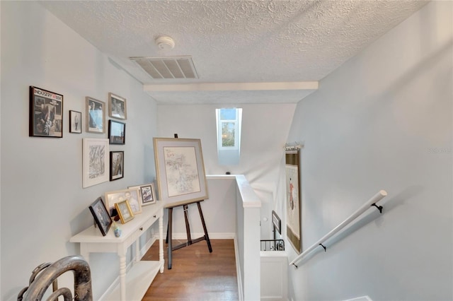 stairway with hardwood / wood-style floors and a textured ceiling