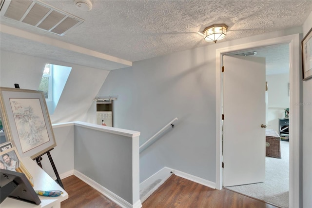 staircase with wood-type flooring and a textured ceiling