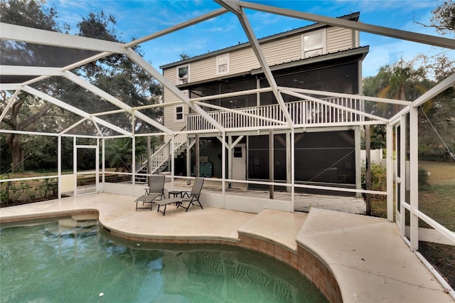 rear view of house with glass enclosure and a patio area