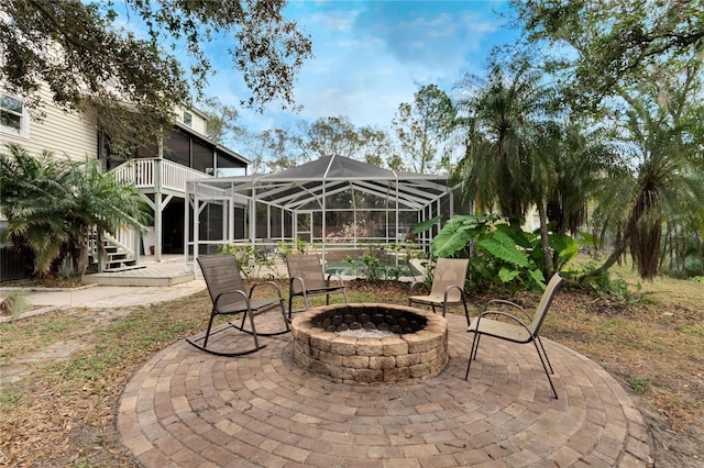 view of patio featuring a wooden deck, a sunroom, and an outdoor fire pit