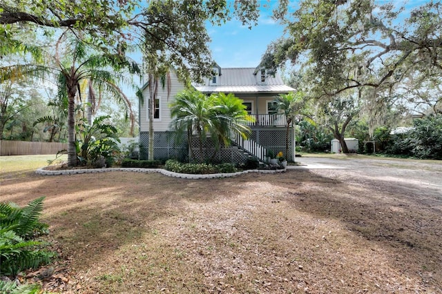 view of front of home with metal roof, fence, stairway, and a porch