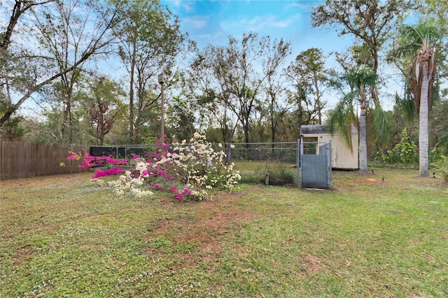 view of yard featuring an outbuilding, a storage shed, and fence