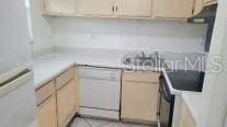 kitchen featuring light brown cabinets, white dishwasher, and fridge