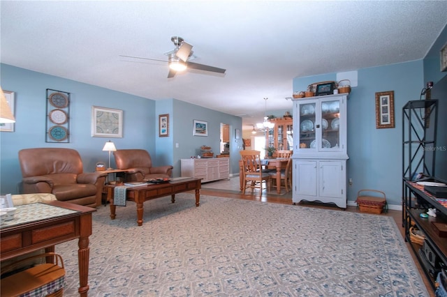 living room with ceiling fan with notable chandelier and a textured ceiling