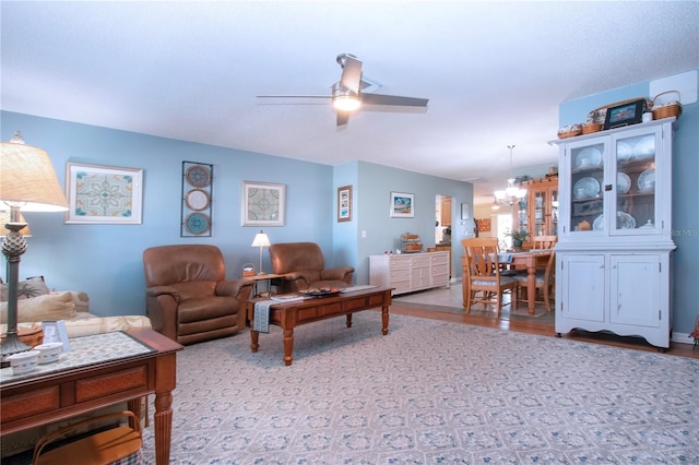 living room featuring ceiling fan with notable chandelier