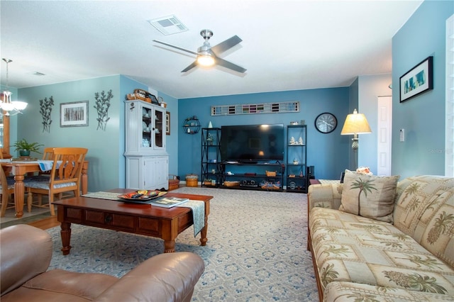 living room featuring carpet and ceiling fan with notable chandelier