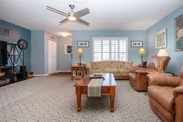 living room featuring ceiling fan, light colored carpet, and a textured ceiling