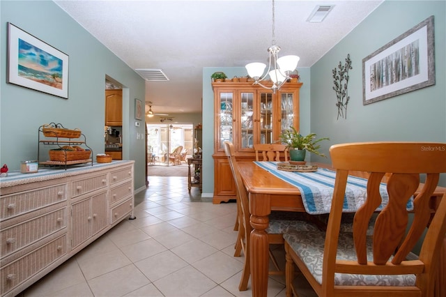 tiled dining space featuring ceiling fan with notable chandelier and a textured ceiling