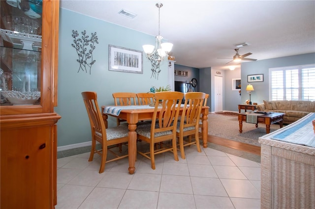 tiled dining space with ceiling fan with notable chandelier