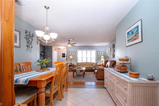 tiled dining area featuring ceiling fan with notable chandelier