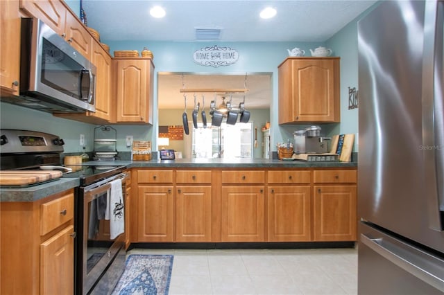 kitchen featuring kitchen peninsula, appliances with stainless steel finishes, a textured ceiling, and light tile patterned floors