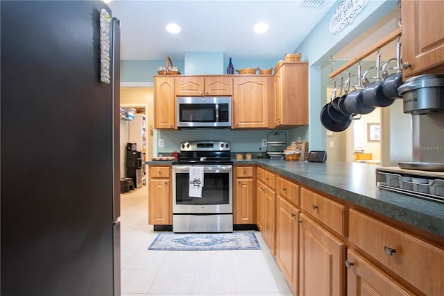 kitchen featuring kitchen peninsula, light tile patterned floors, and appliances with stainless steel finishes