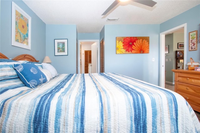 bedroom featuring ceiling fan, a closet, ensuite bathroom, and a textured ceiling