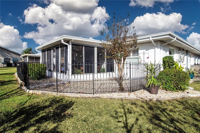 rear view of house featuring a lawn and a sunroom