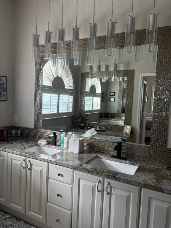 kitchen featuring white cabinets, hanging light fixtures, dark stone counters, and sink