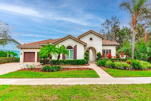 mediterranean / spanish house featuring a front yard and a garage