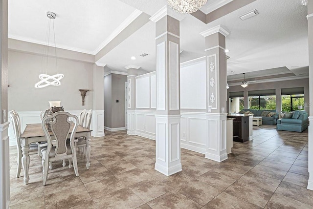 unfurnished dining area featuring ceiling fan with notable chandelier, decorative columns, and ornamental molding