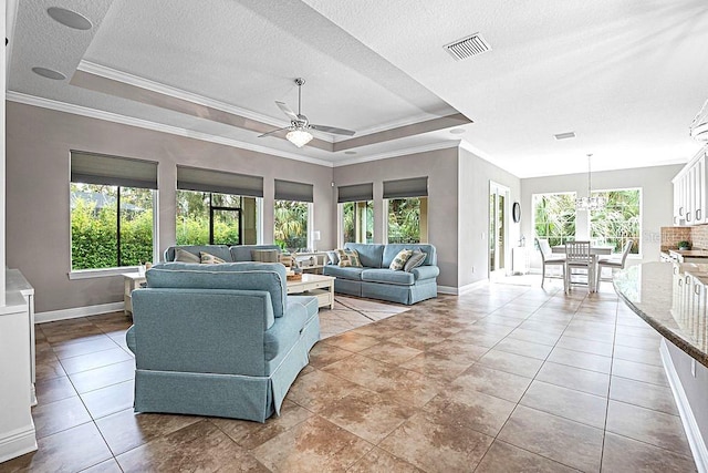 tiled living room with a textured ceiling, ceiling fan with notable chandelier, a tray ceiling, and ornamental molding