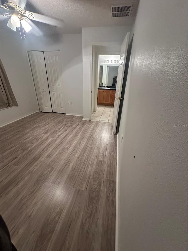 unfurnished room featuring a textured ceiling, light hardwood / wood-style flooring, and ceiling fan