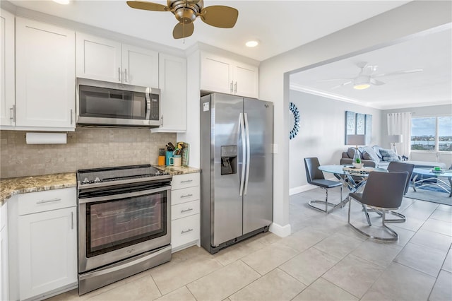 kitchen with backsplash, crown molding, light stone countertops, white cabinetry, and stainless steel appliances