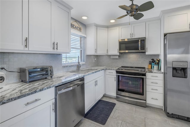 kitchen featuring white cabinets, sink, light tile patterned floors, appliances with stainless steel finishes, and tasteful backsplash