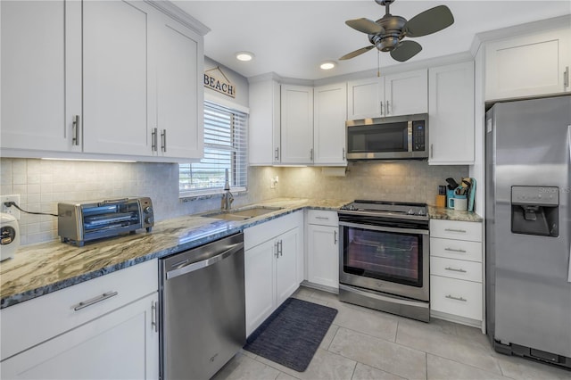 kitchen featuring sink, light stone countertops, light tile patterned floors, appliances with stainless steel finishes, and white cabinetry