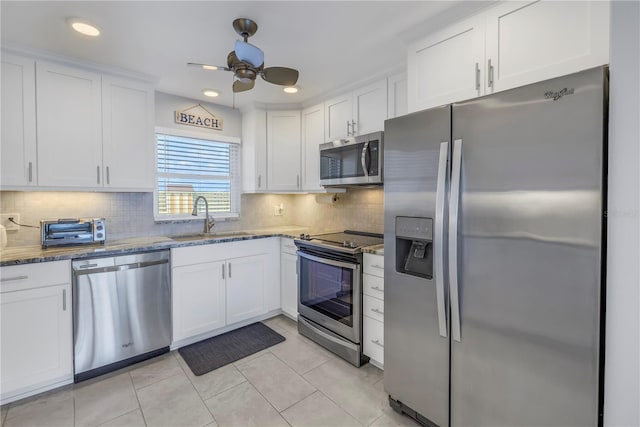 kitchen featuring white cabinetry, sink, light stone countertops, light tile patterned flooring, and appliances with stainless steel finishes