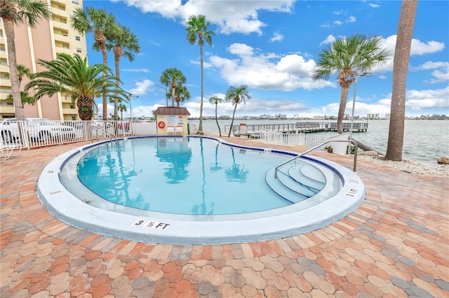 view of pool featuring a patio area, a water view, and a boat dock