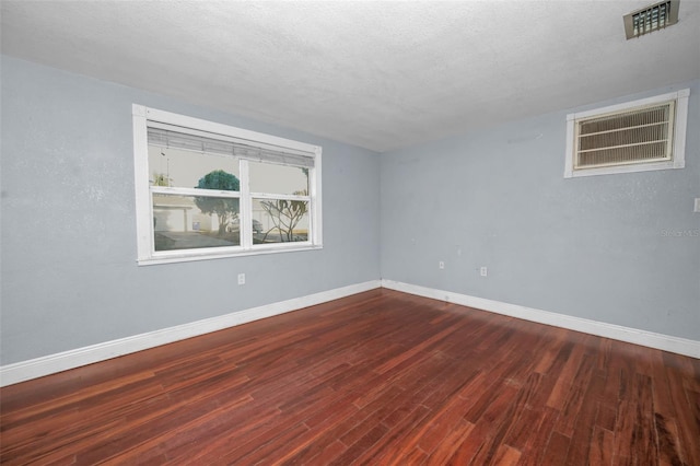 empty room with wood-type flooring and a textured ceiling