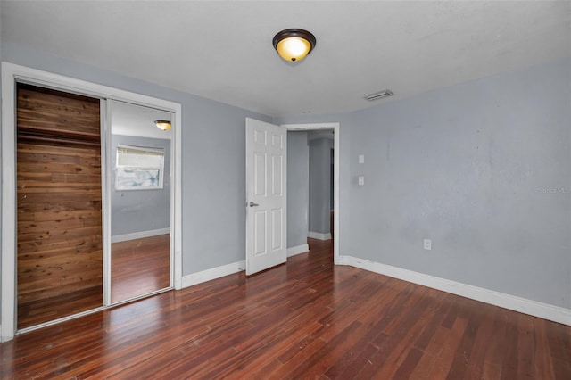 unfurnished bedroom with a closet and dark wood-type flooring