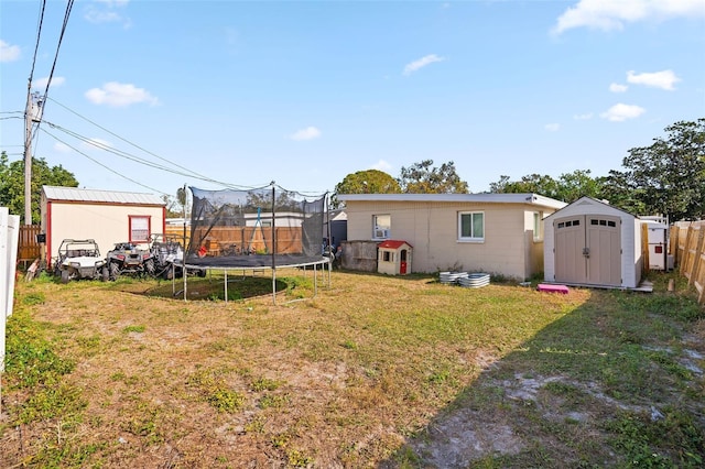 view of yard featuring a trampoline and a storage unit