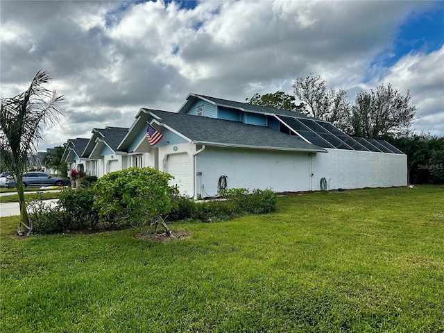 view of side of property featuring glass enclosure, a garage, and a yard