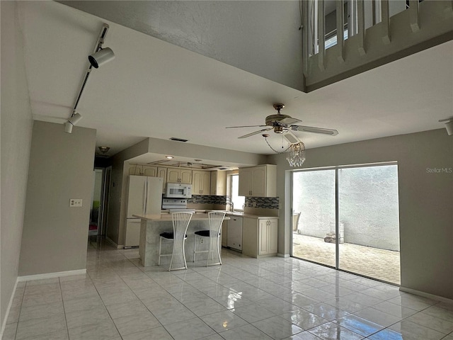 kitchen with white appliances, rail lighting, ceiling fan, light tile patterned floors, and a kitchen island