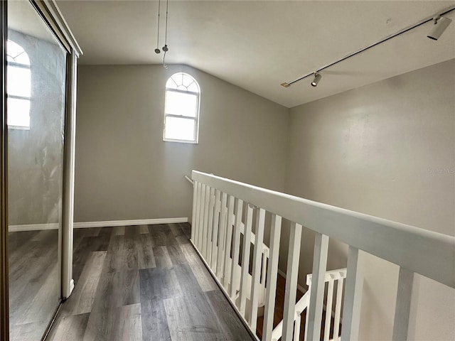 corridor featuring track lighting, dark hardwood / wood-style flooring, and vaulted ceiling