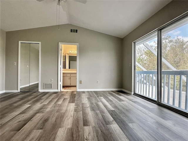 unfurnished bedroom featuring hardwood / wood-style floors, ensuite bath, vaulted ceiling, ceiling fan, and a closet