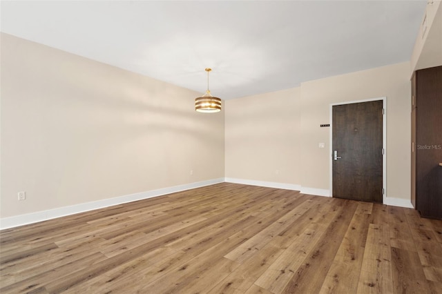 empty room featuring an inviting chandelier and light hardwood / wood-style flooring