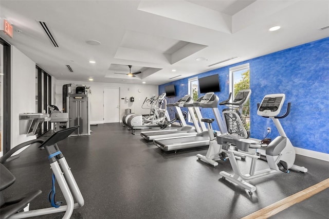 exercise room featuring a raised ceiling and ceiling fan