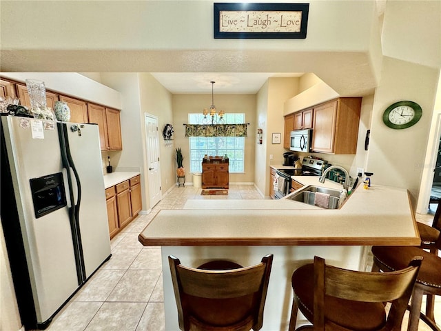 kitchen with sink, stainless steel appliances, kitchen peninsula, a chandelier, and decorative light fixtures