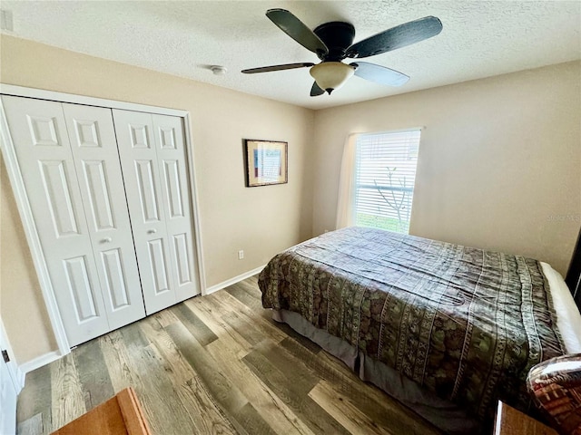 bedroom with a closet, ceiling fan, light hardwood / wood-style flooring, and a textured ceiling