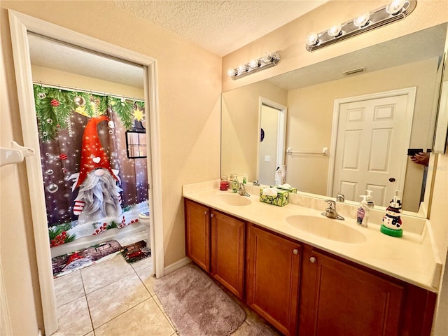 bathroom featuring tile patterned floors, vanity, toilet, and a textured ceiling