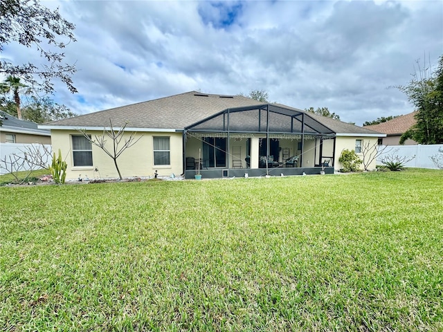 rear view of house with a lawn and glass enclosure