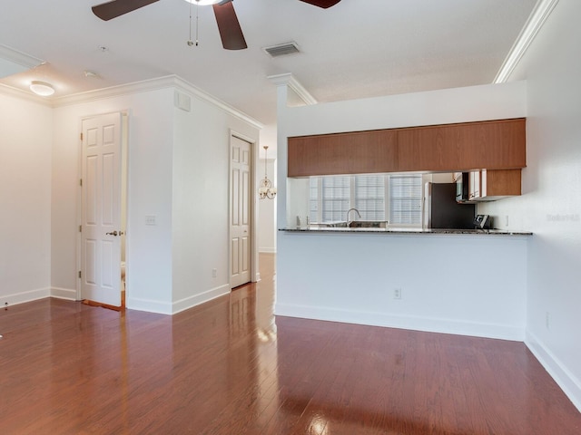 interior space with kitchen peninsula, stainless steel fridge, ceiling fan, crown molding, and dark wood-type flooring