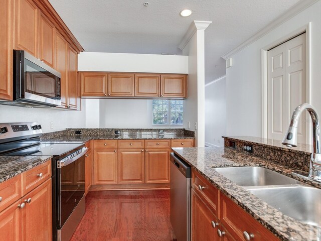 kitchen featuring sink, stainless steel appliances, dark hardwood / wood-style flooring, a textured ceiling, and ornamental molding