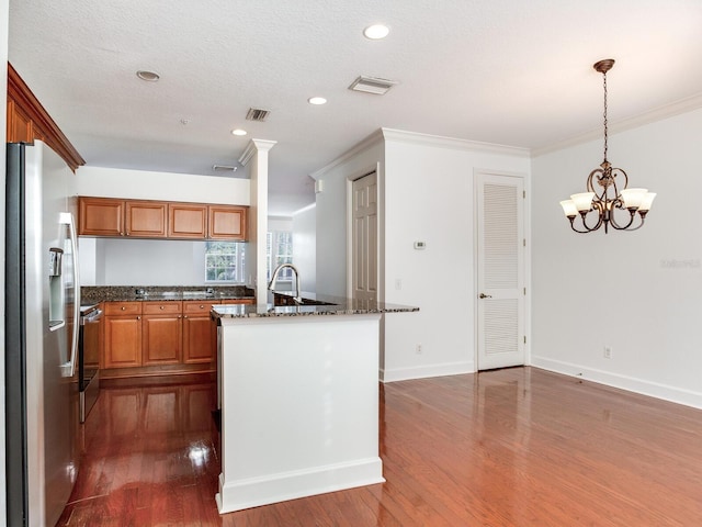 kitchen featuring hanging light fixtures, dark hardwood / wood-style floors, stainless steel refrigerator with ice dispenser, a notable chandelier, and dark stone counters