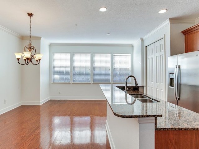 kitchen with light wood-type flooring, sink, pendant lighting, an inviting chandelier, and dark stone countertops