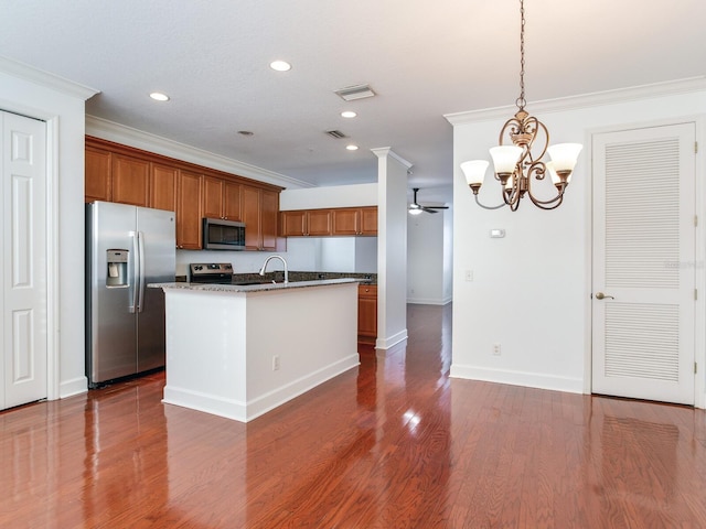 kitchen featuring ceiling fan with notable chandelier, stainless steel appliances, a kitchen island with sink, dark wood-type flooring, and decorative light fixtures