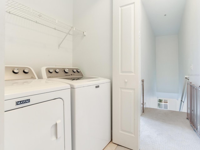 clothes washing area with light carpet and washer and clothes dryer